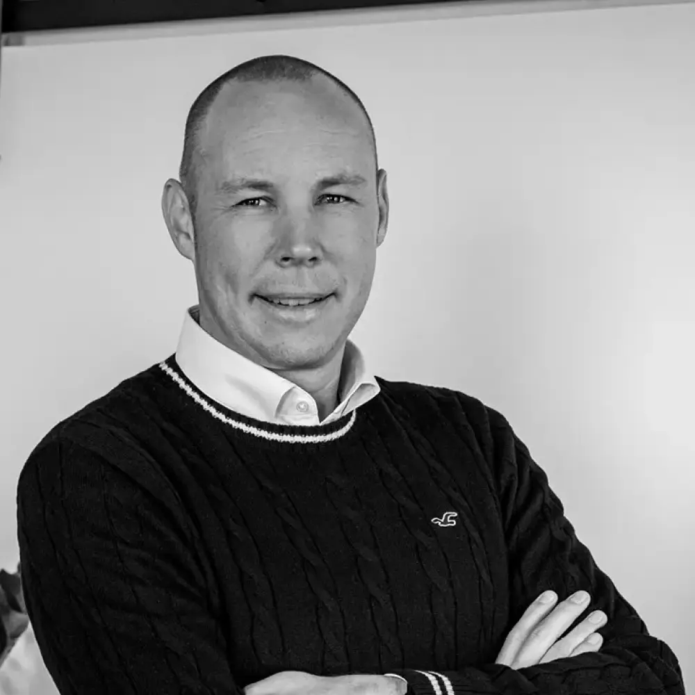 Mitarbeiter mit kurz rasiertem Haar, Pullover und Hemd, verschränkte Arme – STUDIO S Architekten Bocholt